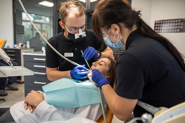 Girl at the dentist with an assistant receives treatment with the help of the latest equipment