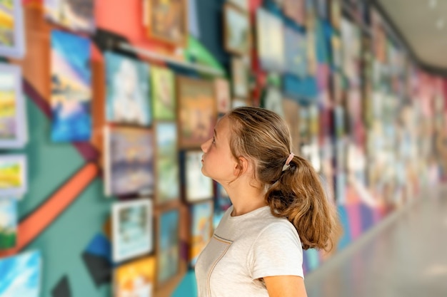 A girl on display at an art gallery looks at fine art