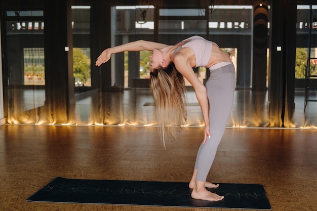 The girl does yoga A woman in sports clothes does yoga exercises in the gym