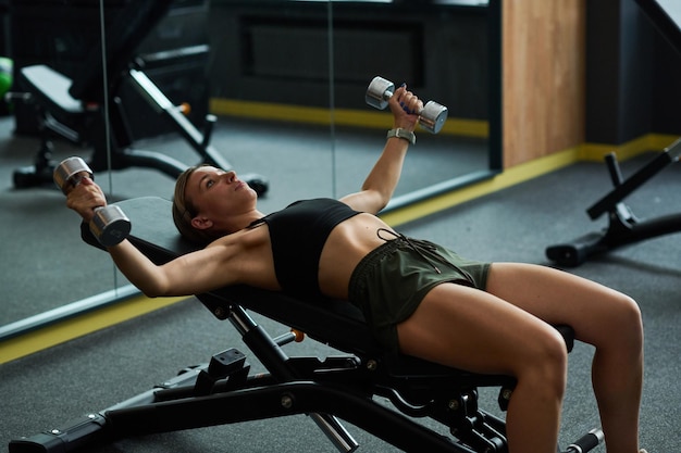 Girl doing exercises with dumbbells in gym