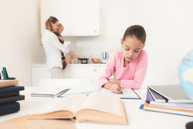 Girl doing homework mom stands behind.