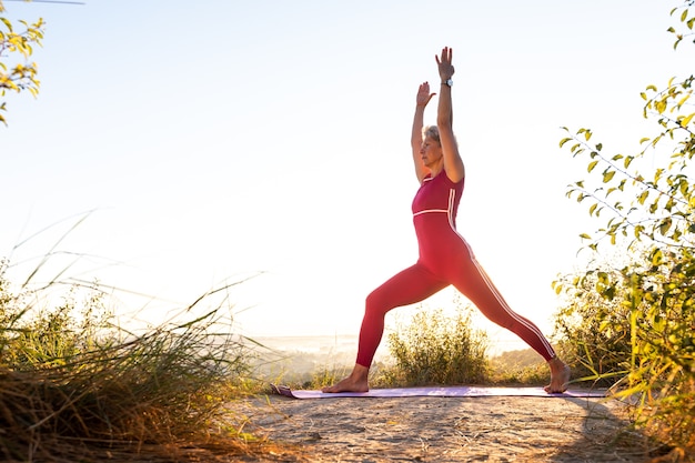 Girl doing yoga exercise two hands up on a sports mat at sunrise