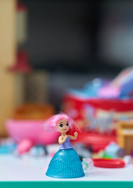 Girl doll on table on blur toys background