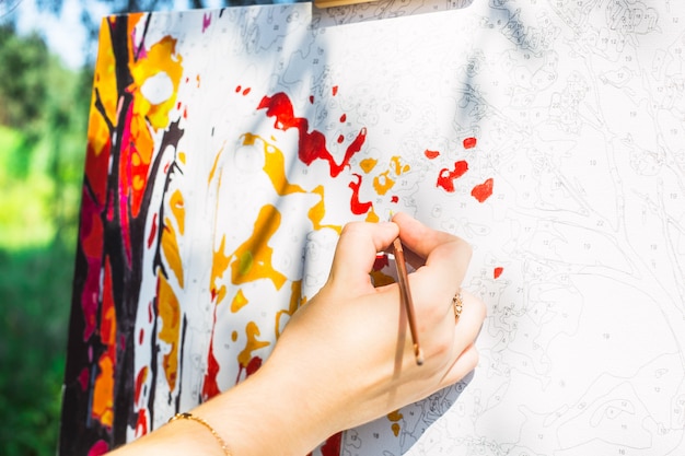 The girl draws a yellow paint brush on the canvas with numbers with the brush