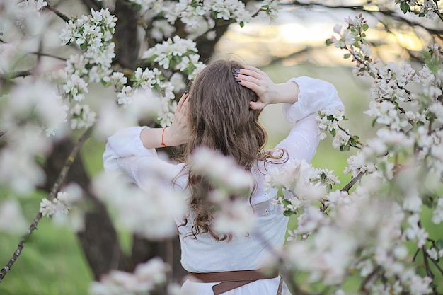 girl dreams back view, spring portrait happy girl in blooming garden, seasonal april