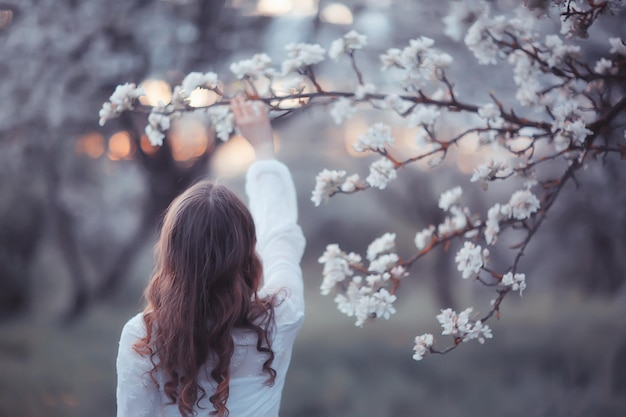 girl dreams back view, spring portrait happy girl in blooming garden, seasonal april