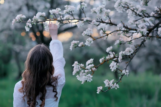 girl dreams back view, spring portrait happy girl in blooming garden, seasonal april