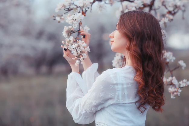 girl dreams back view, spring portrait happy girl in blooming garden, seasonal april