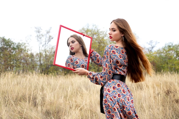 girl in a dress in flowers with a mirror