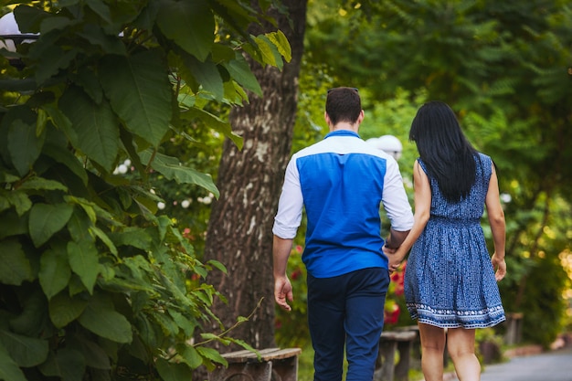 Girl in a dress and a man in a shirt and trousers walk in the park