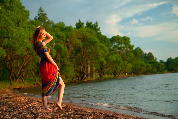 Girl in dress walking on the sea coast in the trees along the sandy beach