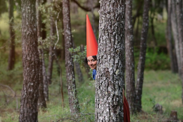 Girl dressed as a gnome in the woods looks through the trees