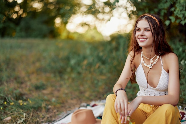 Girl dressed as a hippie eco relaxing in the park sitting on a blanket in the sunset relaxed lifestyle