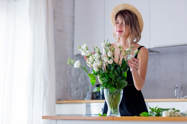 girl dressed in a black dress near white roses bouquet in a vase