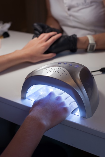 Girl dries nail Polish in a UV lamp.