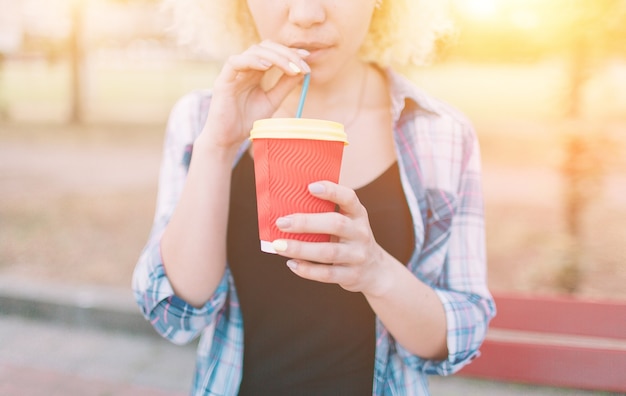 Girl drinking coffee from a paper cup through a straw