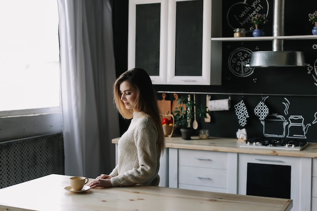 a girl drinking coffee in the kitchen at home in the morning