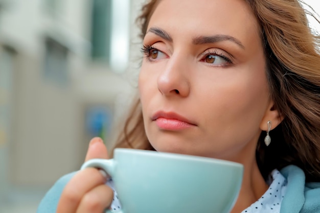 Girl drinking coffee on the street a cup of coffee a cup of coffee and a girl's face closeup