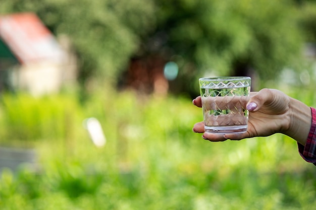 Girl drinks water from a glass, outdoors. Selective focus