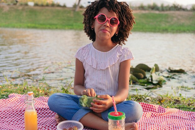 Girl eating healthy salad from a glass container by the lake