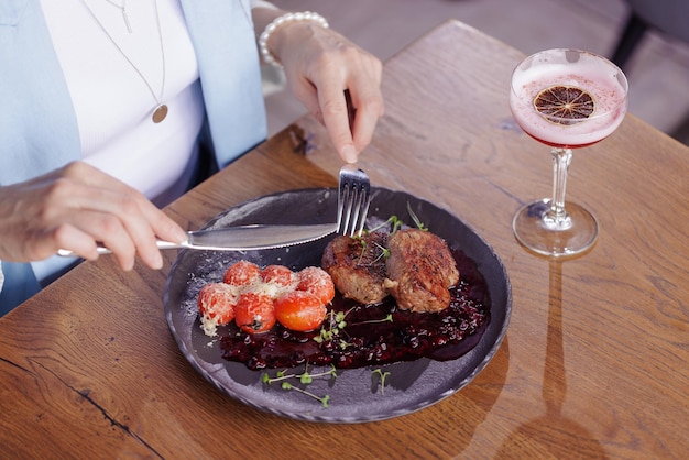 Girl eating meat medallion with tomatoes closeup in a modern restaurant