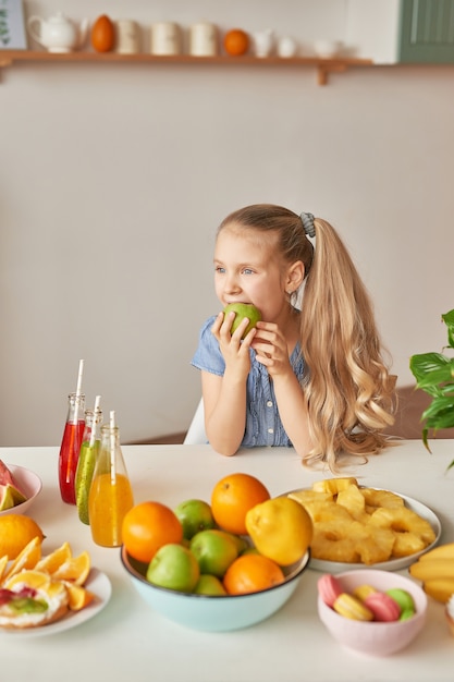 Girl eats fruit on a table full of food