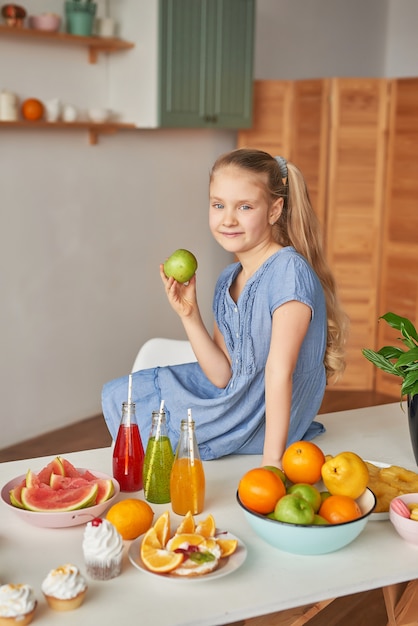 Girl eats fruit on a table full of food