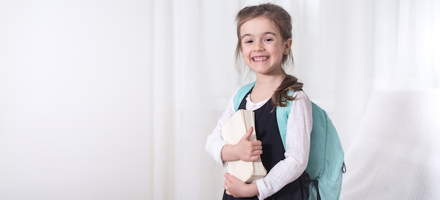 Girl-elementary school student with a backpack and a book