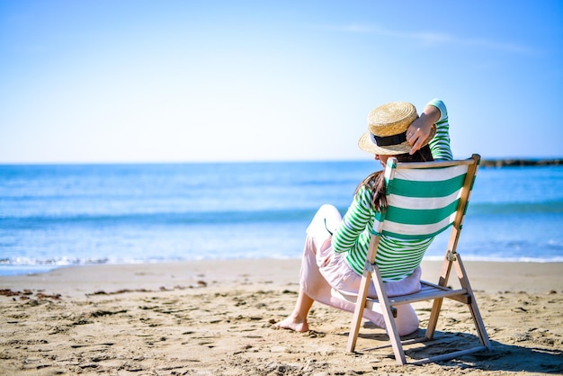 girl enjoy sunset by the sea in a vintage deck chair