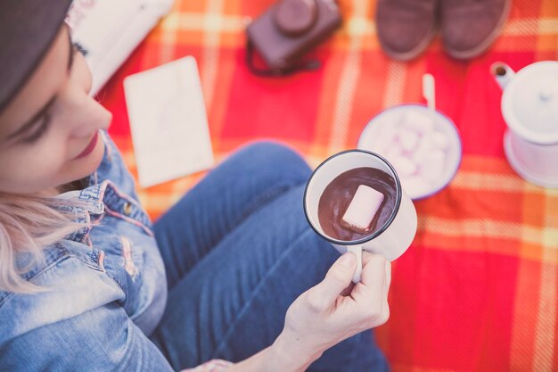 A girl enjoying a cup of hot cocoa and a marshmallow outdoors