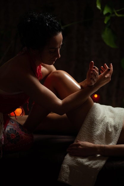 Girl enjoying therapeutic massage with oil in spa with dark lighting, closeup