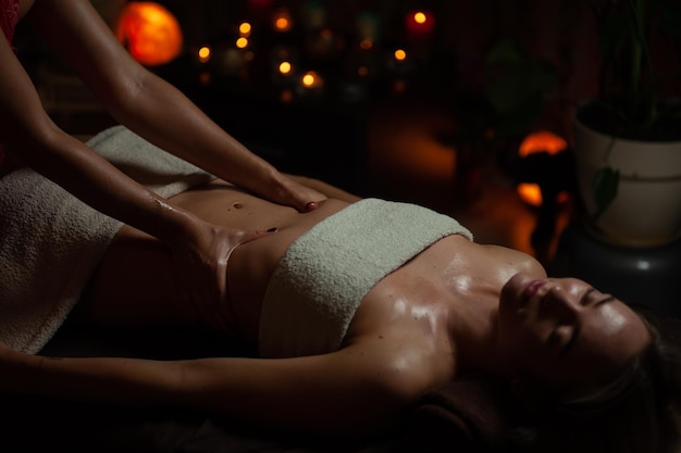 Girl enjoying therapeutic massage with oil in spa with dark lighting, closeup