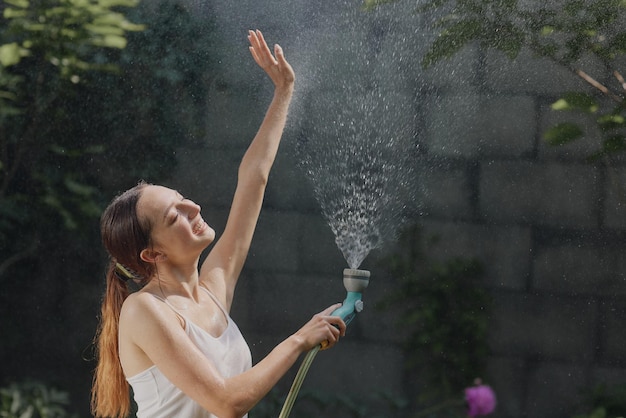 Girl enjoying water in the heat of summer in the garden