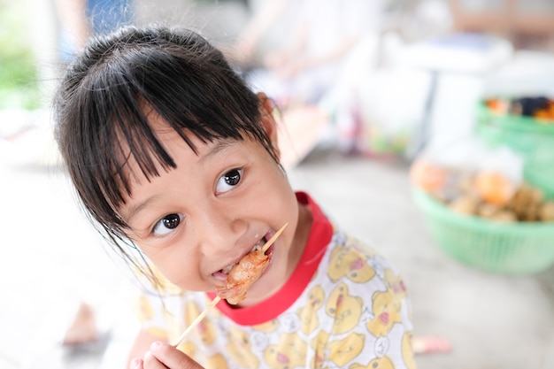 Girl enjoys eating grilled pork