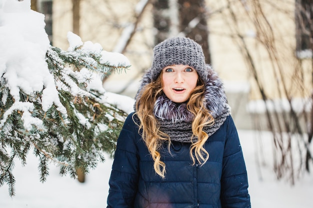 A girl of European appearance walks in the Park, forest, winter and snow, dressed in warm clothes, hat, jacket, scarf, rest, Hiking