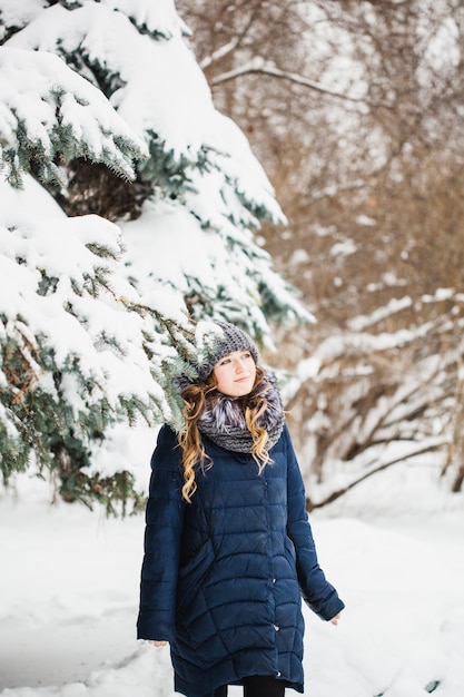 A girl of European appearance walks in the Park, forest, winter and snow, dressed in warm clothes, hat, jacket, scarf, rest, Hiking