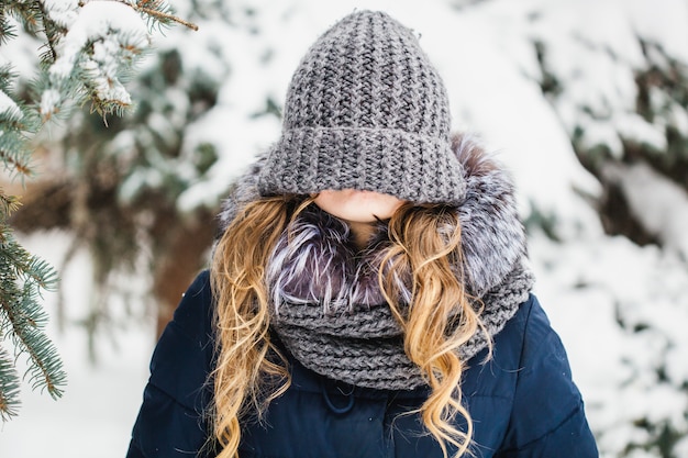 A girl of European appearance walks in the Park, forest, winter and snow, dressed in warm clothes, hat, jacket, scarf, rest, Hiking