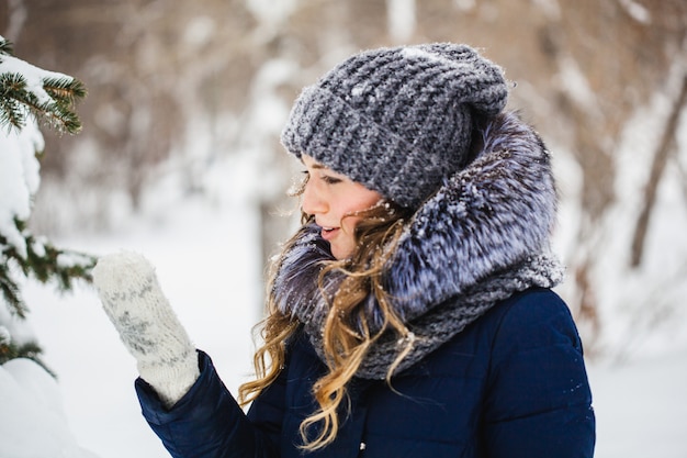 A girl of European appearance walks in the Park, forest, winter and snow, dressed in warm clothes, hat, jacket, scarf, rest, Hiking