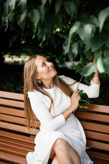 Girl European looks, in the foliage of a Bush or tree