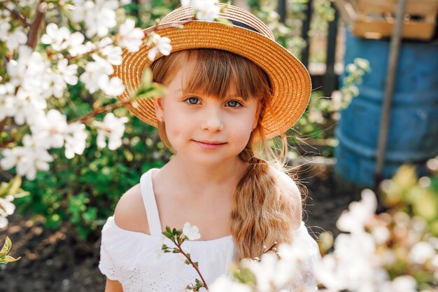 Girl farmer in a hat in the garden is engaged in gardening, spring flowering of apricots. A garden in bloom. High quality photo