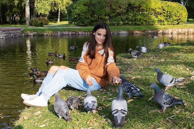 A girl feeds ducks on the shore of a pond