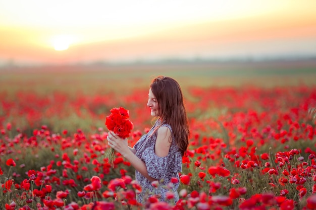 a girl in a field with poppies in her hands smiles