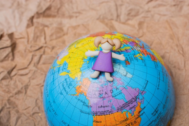 Girl figurine on top of globe as education and business concept