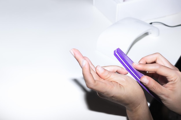 Girl filing her nails on the white table