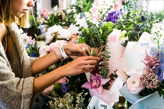 The girl florist corrects the bouquets of flowers on the counter. Flower market