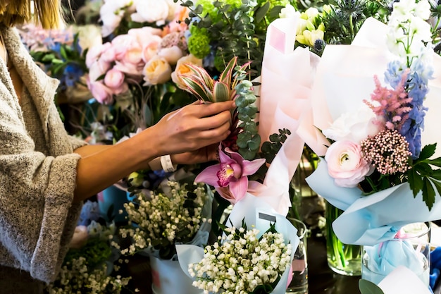 The girl florist corrects the bouquets of flowers on the counter