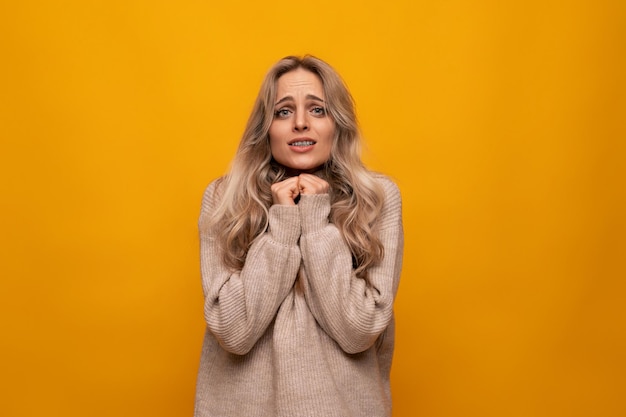 The girl folded her hands and asks for help on a yellow background