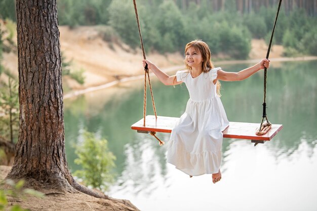 Photo a girl in the forest swinging on a swing rope swing on a forest lake