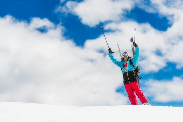 Girl freeride skier raises his hands before the descent from the top