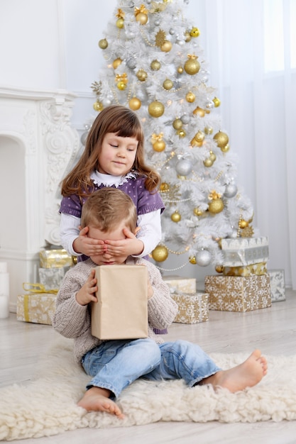 The girl gave a gift to her brother and closes his eyes